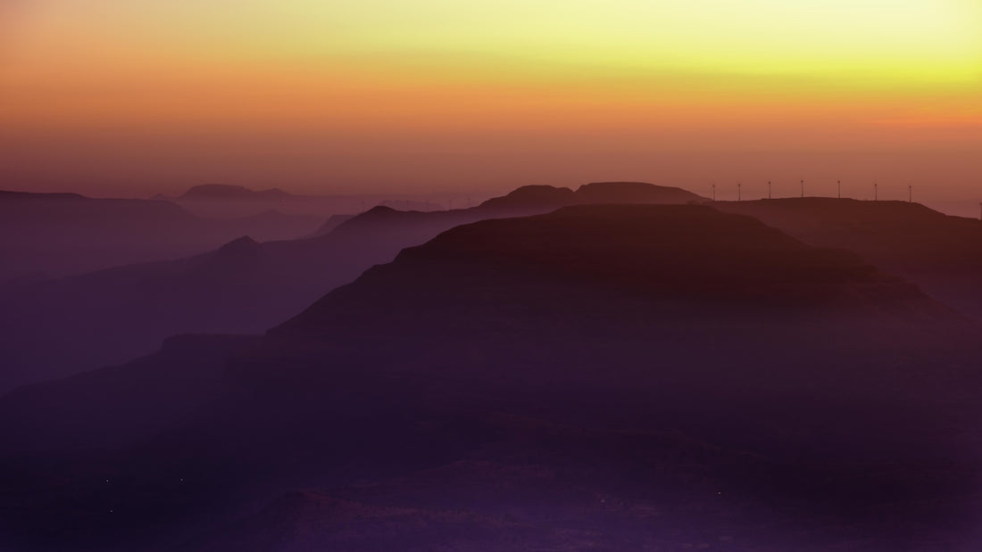 the sun is setting over a mountain range